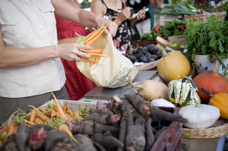 Head and torso of people purchasing fresh produce at the King's Garden Kitchen shop.