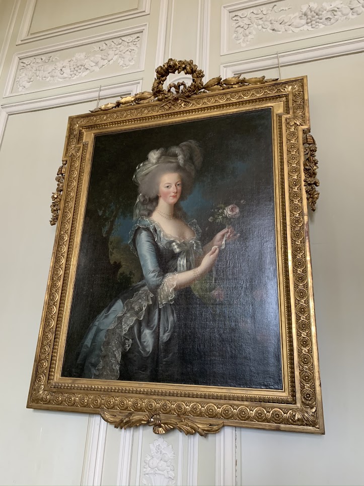 Painting of Marie Antoinette in period clothes with a pink rose in hear hand.