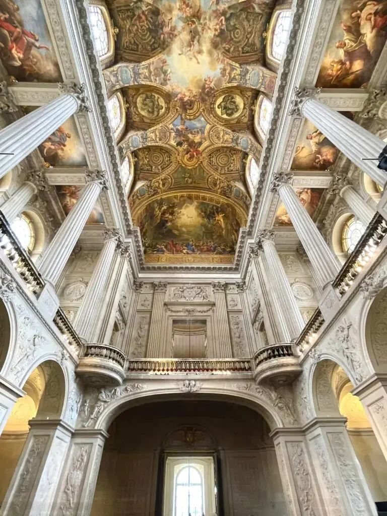"Interior of the Royal Chapel at the Palace of Versailles, showcasing soaring Corinthian columns, arched balconies, and ceiling frescoes.