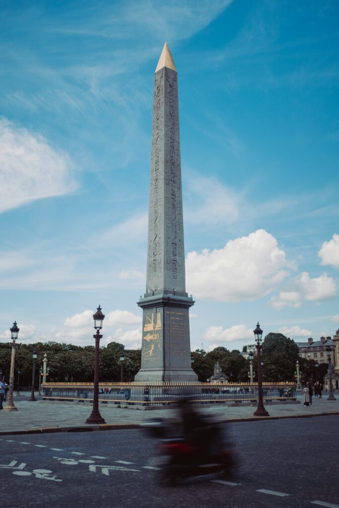 "The Luxor Obelisk stands tall in the center of Place de la Concorde, Paris, under a vivid blue sky. Once the site of the guillotine during the French Revolution, this square marks the tragic end of Marie Antoinette's life—an essential stop when walking in the footsteps of the ill-fated queen.