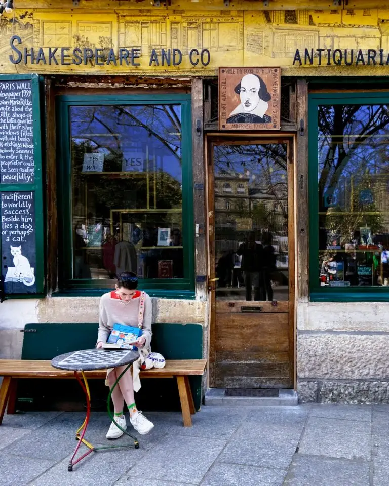Exterior of the famous Shakespeare and Company bookstore in Paris with a woman reading outside