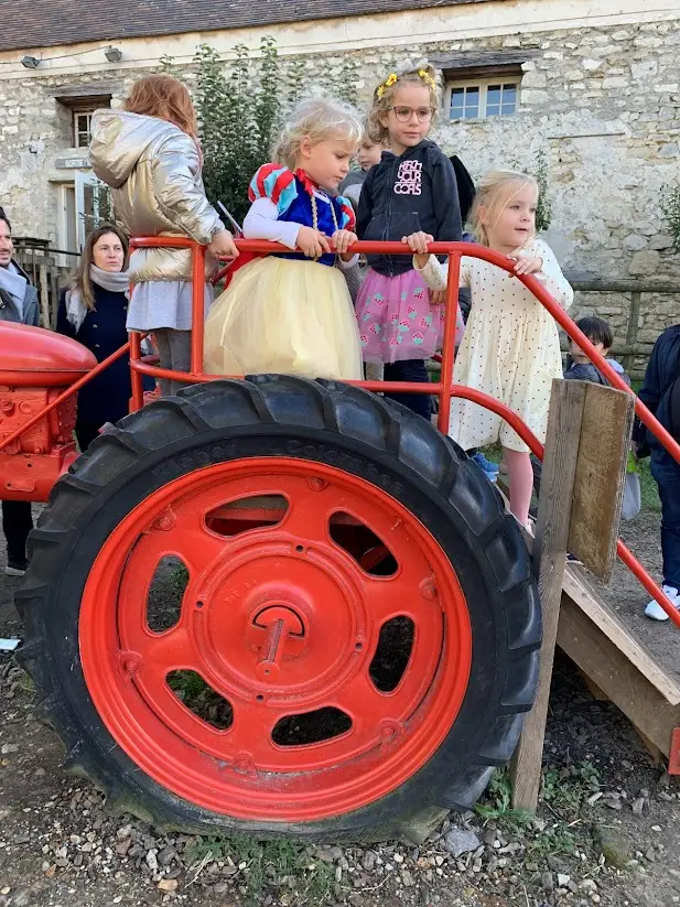 Children climb aboard a vintage red tractor at a farm event near Versailles. Engaging farm outings and interactive play areas like this are favorite weekend activities for families exploring the region together.