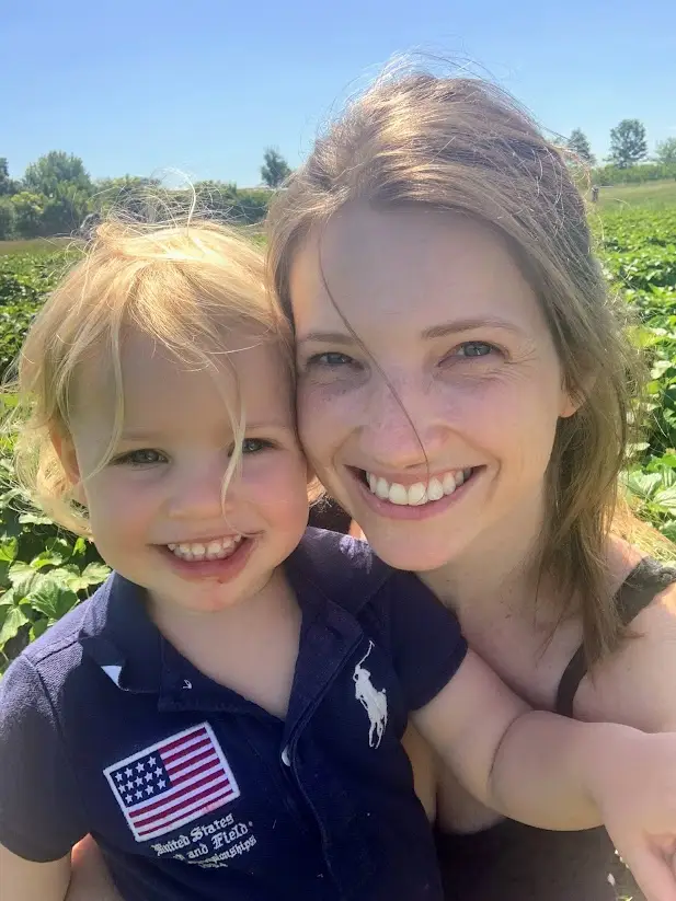 A smiling mother and her young child enjoy a sunny day of strawberry picking in the countryside near Versailles. Outdoor farms like this are a popular choice for family weekend activities near Versailles, offering hands-on fun and fresh air for all ages.