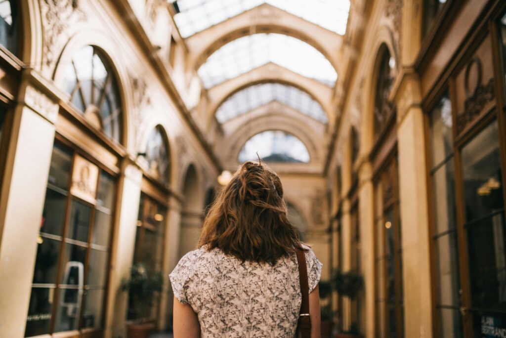 Shot of lady's back, facing a Parisian row of shops.