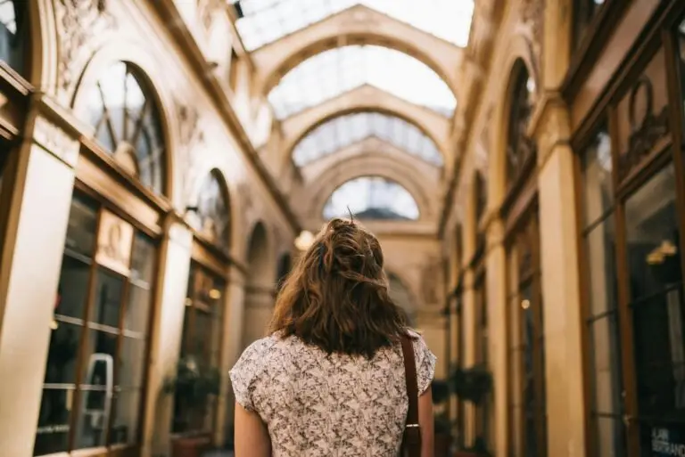 American traveler exploring a historic covered passage in Paris, admiring French architecture and cultural charm. She's exploring the cultural differences Americans should know before traveling to Paris.