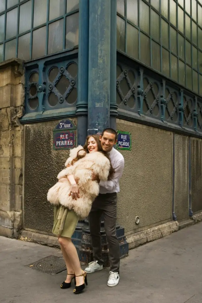 Smiling couple embracing on a Paris street corner in the Marais district, near Rue Perrée and Rue de Picardie.
